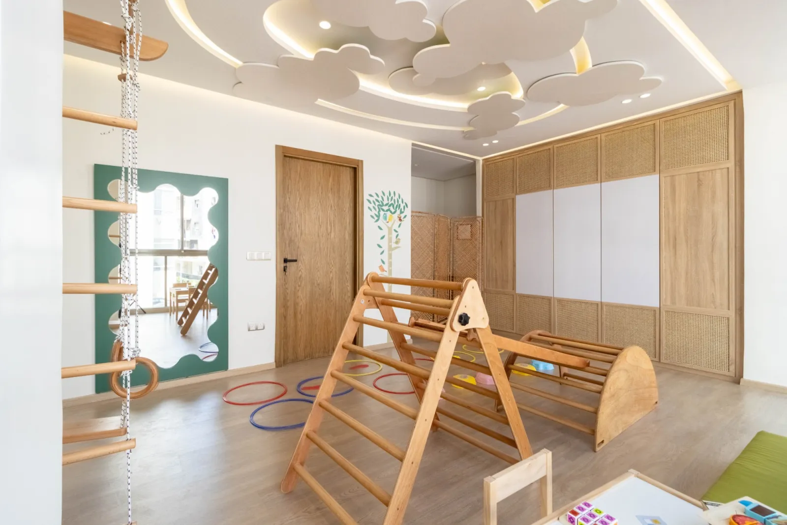 Salle de psychomotricité avec échelle, triangle de motricité et cerceaux au sol